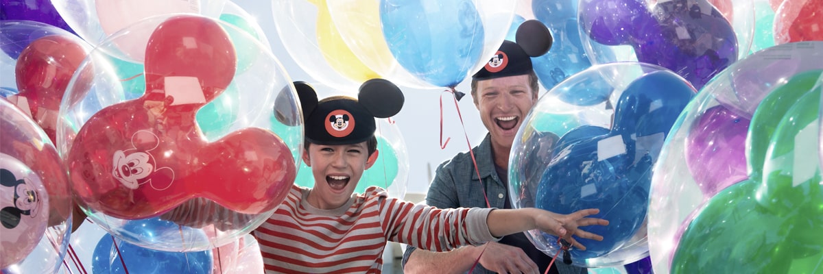 A man and young boy wearing Mickey Mouse hats.